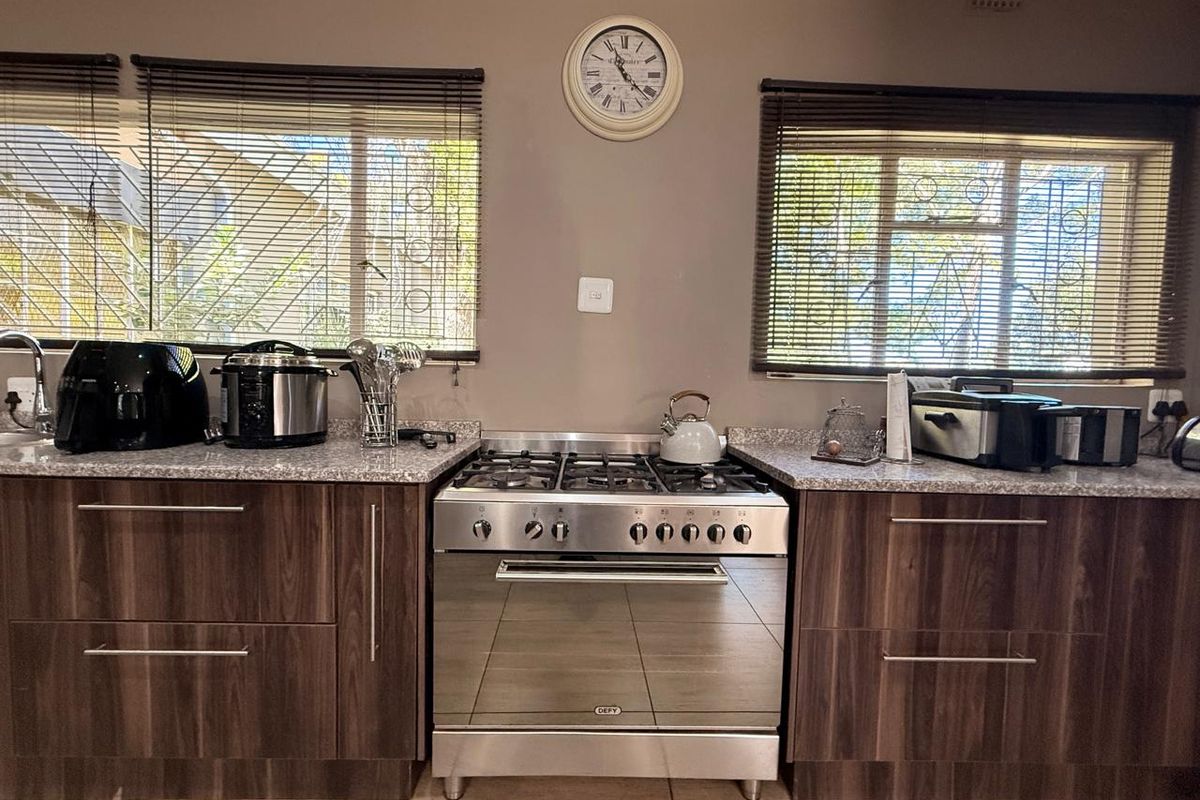 A functional kitchen featuring dark wood-grain cabinetry, granite-look countertops, and a stainless steel freestanding gas stove with an oven.