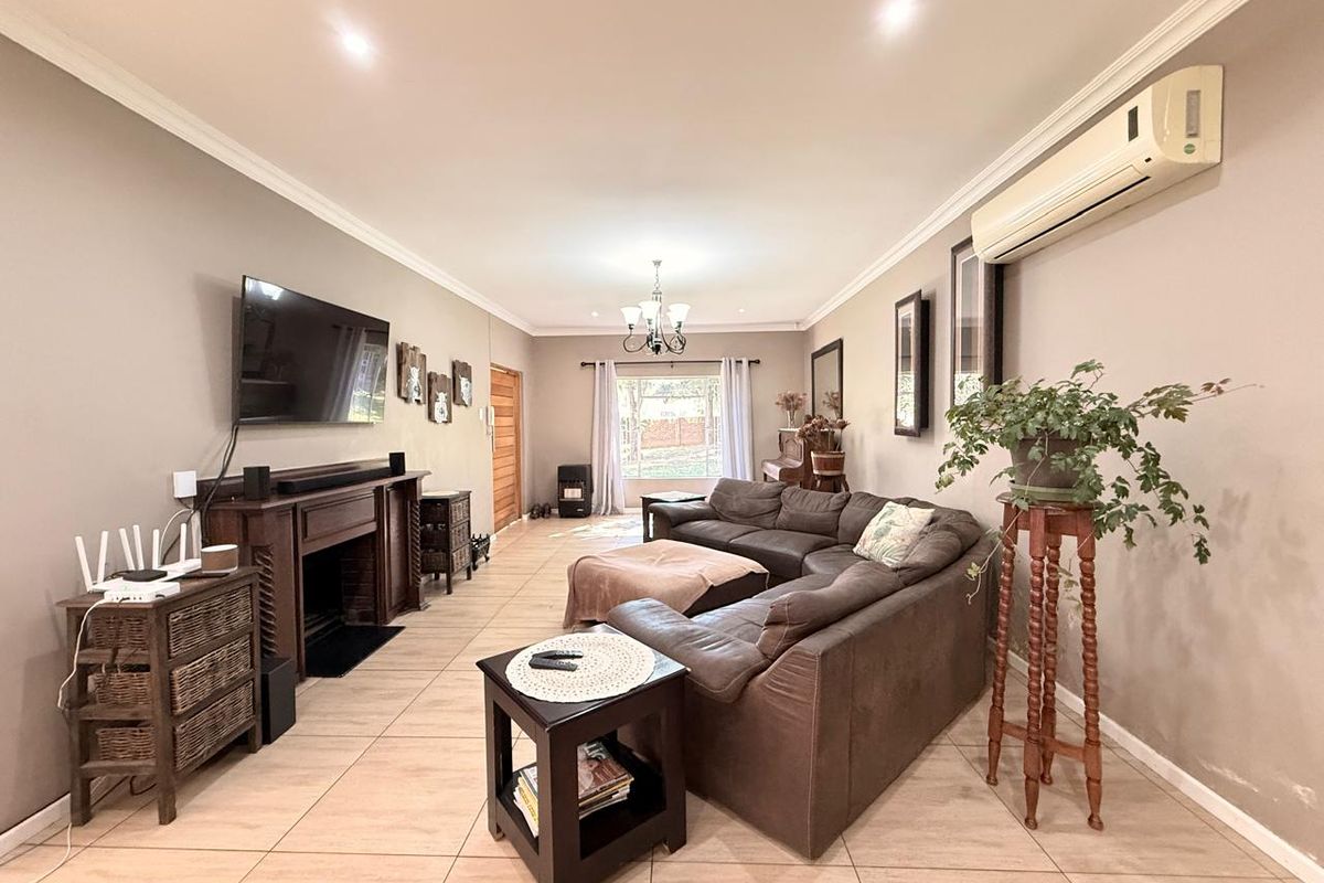 Spacious living room featuring tiled flooring, a built-in fireplace, recessed ceiling lighting, and a wall-mounted air conditioning unit.