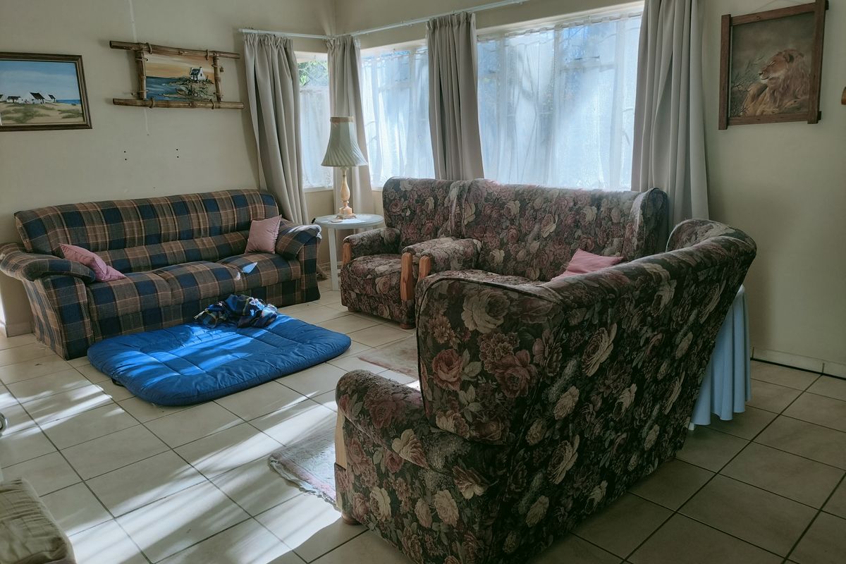 A spacious living room featuring large windows that allow for natural light, finished with neutral floor tiles throughout.