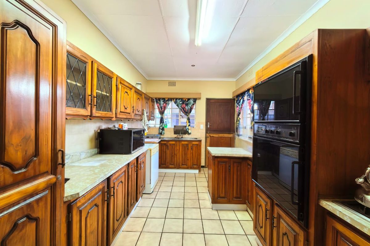 A traditional kitchen featuring extensive solid wood cabinetry, laminate countertops, tiled flooring, and a built-in eye-level oven.