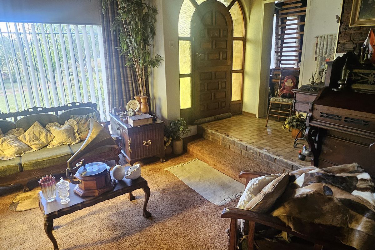 A living room area featuring an arched front door, parquet flooring, and a brick step transition, currently styled with traditional decor.