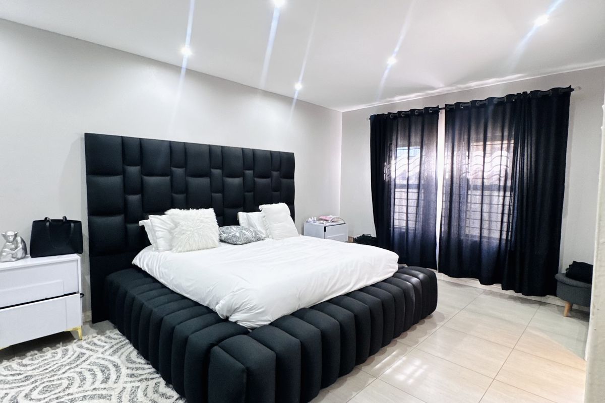 Spacious bedroom featuring neutral tiled flooring, recessed ceiling lighting, and large windows with dark curtains, providing a clean and modern foundation.