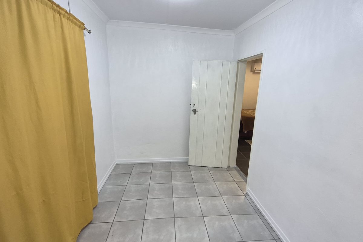 A simple, tiled bedroom featuring white walls, a single door, and a curtained area, offering a clean and neutral space.