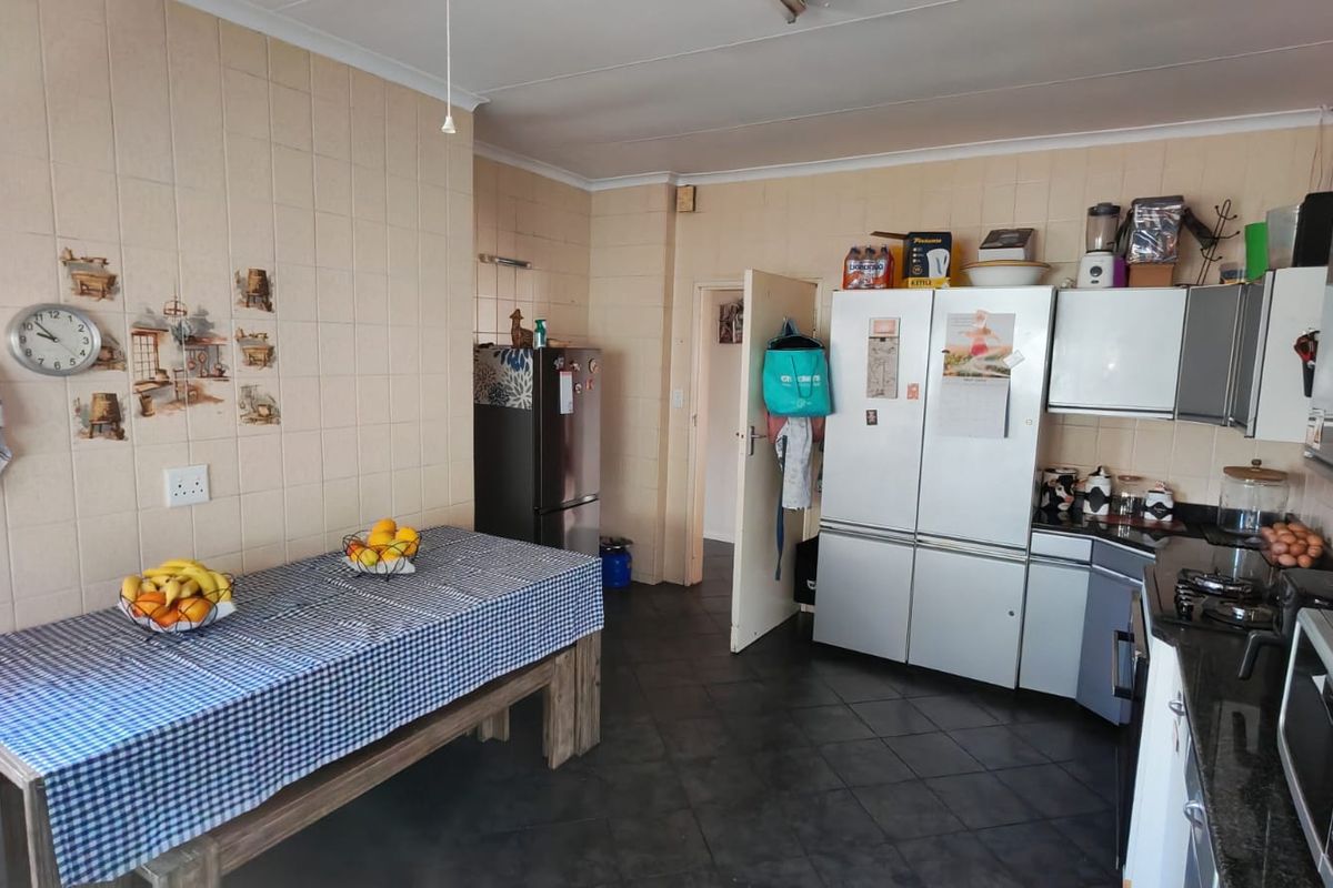 A functional kitchen featuring tiled walls, built-in cabinetry, and dark floor tiles, offering a practical layout for daily meal preparation.