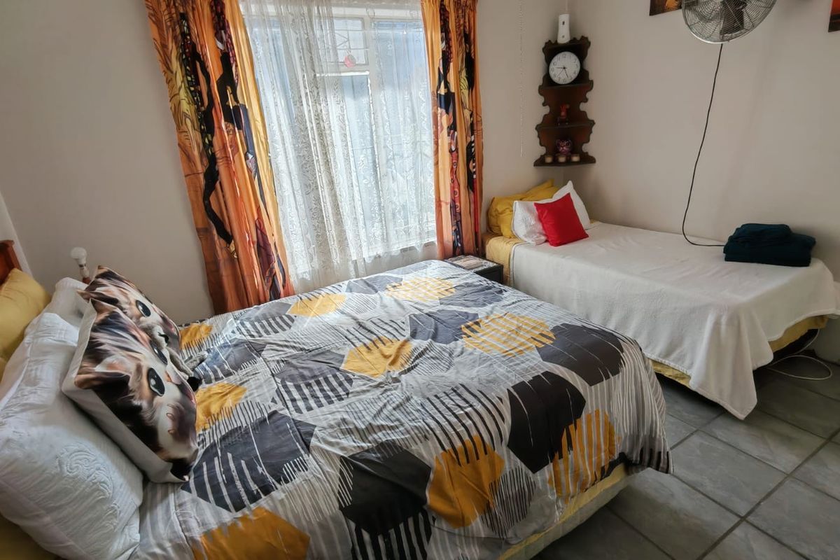 A bedroom featuring tiled flooring and a window with curtains, providing a functional space for sleeping arrangements.