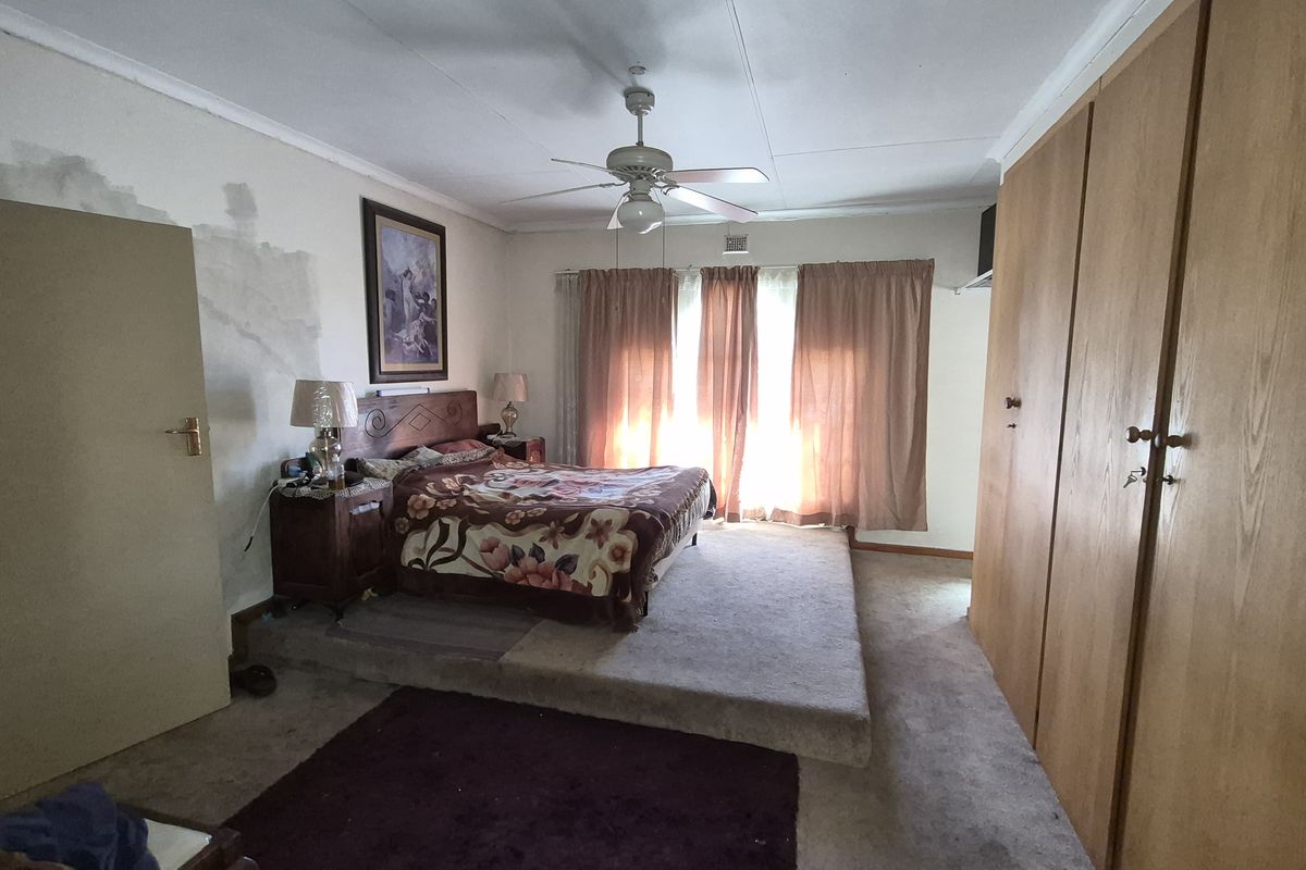 Spacious bedroom featuring a raised platform area, built-in wooden cabinetry, and a ceiling fan.