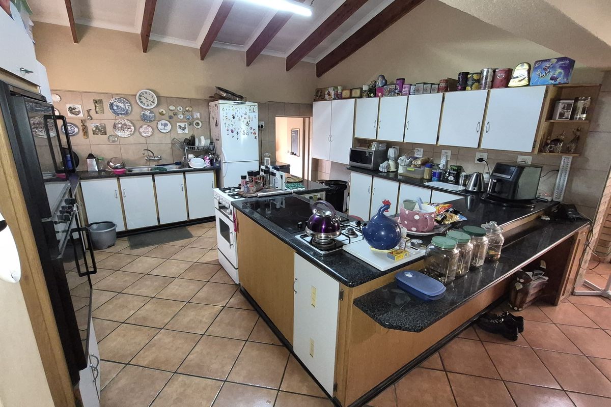 Spacious kitchen featuring a large central island, granite countertops, ample cabinetry, and exposed timber ceiling beams, offering a functional layout for cooking and entertaining.