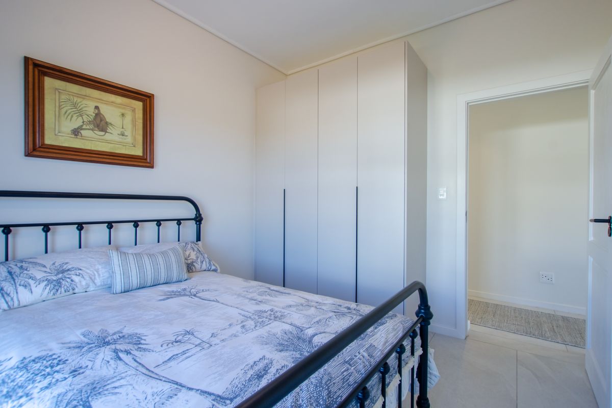 A bright bedroom featuring built-in floor-to-ceiling wardrobes and neutral tiled flooring, offering a clean and functional living space.