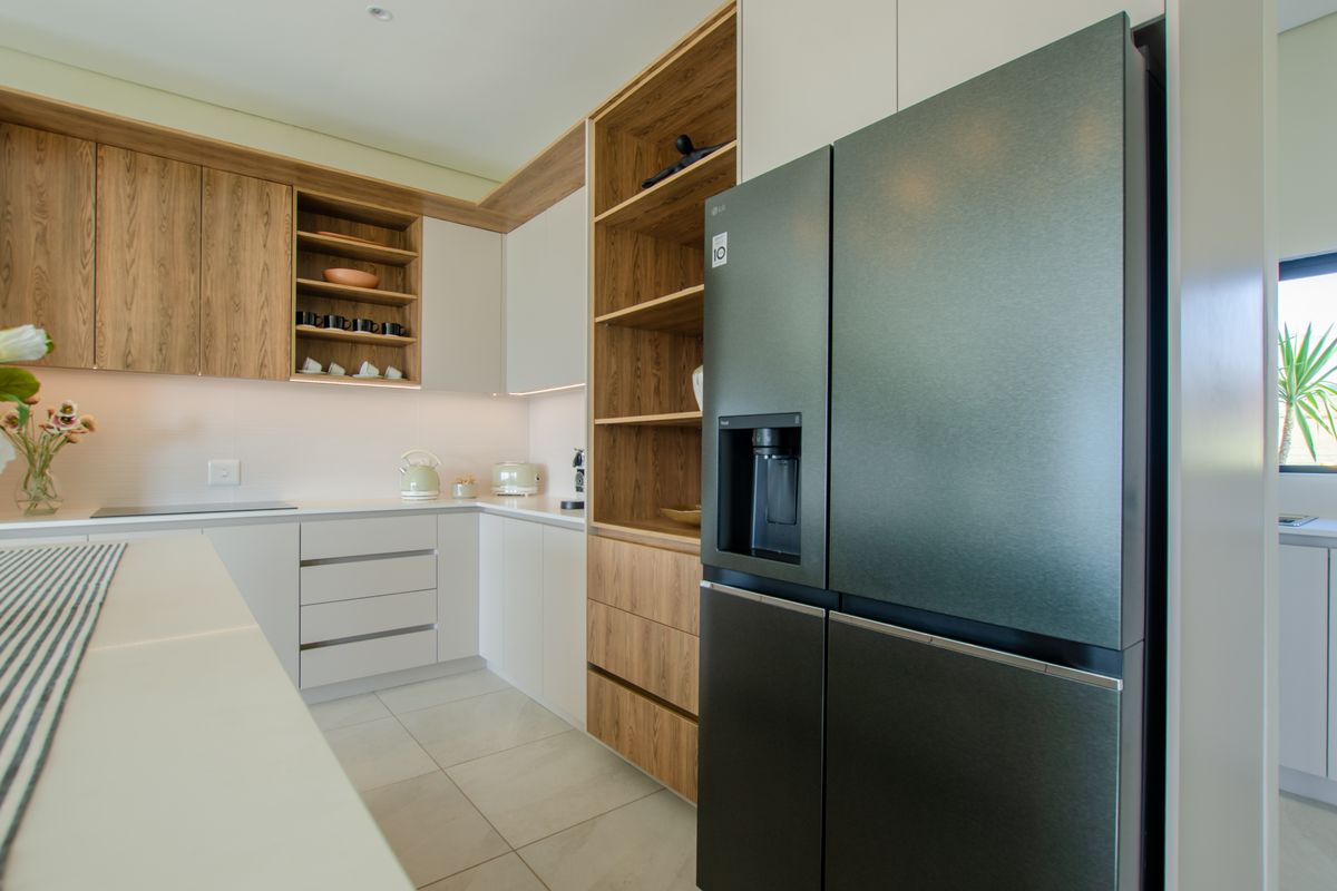 Modern kitchen featuring sleek white cabinetry, wood-grain open shelving, integrated appliances, and a large double-door refrigerator.