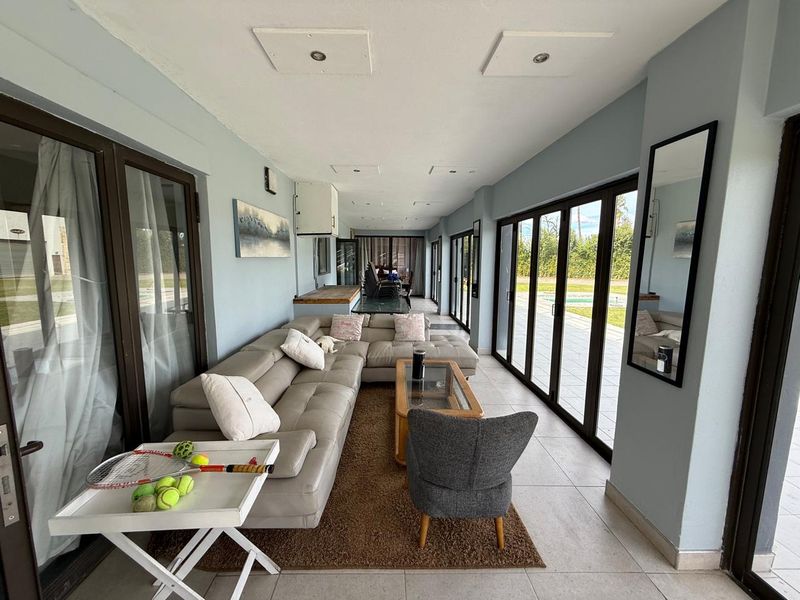 Spacious open-plan living area featuring large glass sliding doors that provide seamless access to the outdoor patio and pool area.
