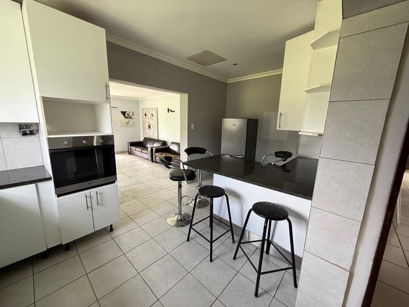 Open-plan kitchen featuring granite countertops, built-in oven, and a breakfast bar, flowing seamlessly into the adjacent living area.