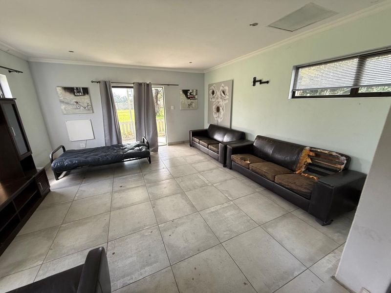 Spacious living area featuring large format floor tiles, recessed ceiling lighting, and direct access to the outdoor area through a sliding glass door.