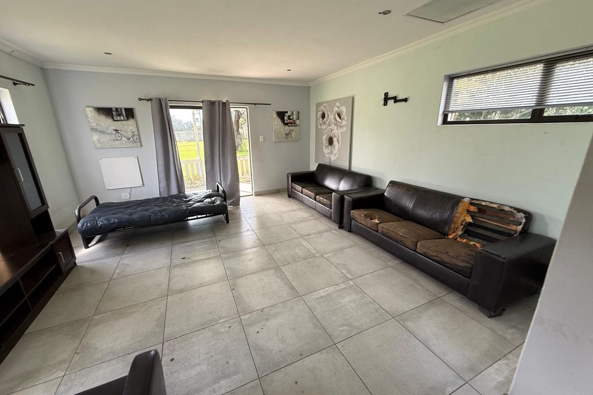 Spacious living area featuring large format floor tiles, recessed ceiling lighting, and direct access to the outdoor area through a sliding glass door.