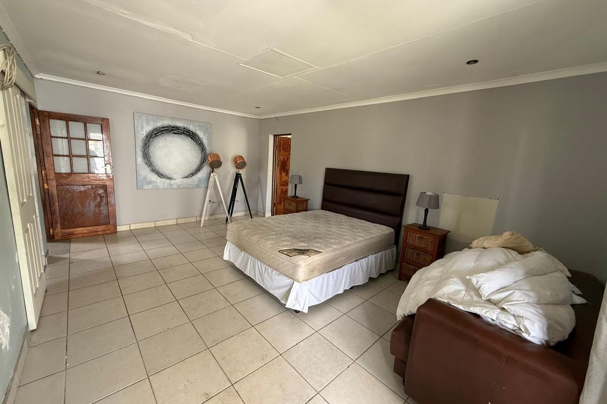 Spacious bedroom featuring tiled flooring, recessed ceiling lighting, and direct access through a wooden door.