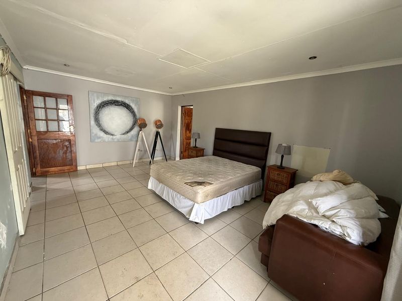 Spacious bedroom featuring tiled flooring, recessed ceiling lighting, and direct access through a wooden door.