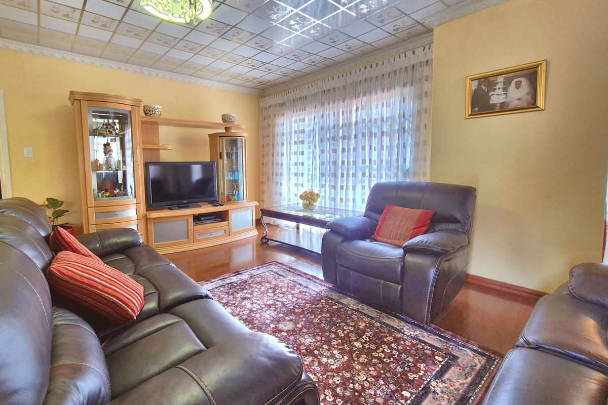 A comfortable living room featuring wood-look flooring and a large window with sheer curtains, providing a bright and inviting space for relaxation.