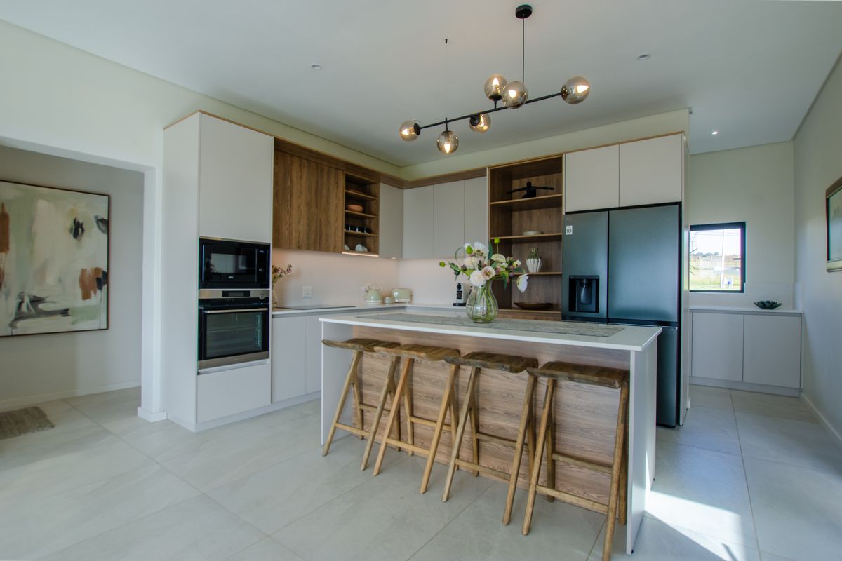 Modern kitchen featuring two-tone cabinetry, a central island with breakfast bar seating, built-in oven, microwave, and integrated lighting.