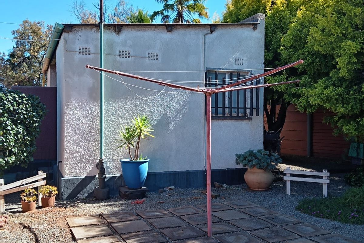 Rear exterior area featuring a paved patio section, gravel landscaping, and a rotary clothesline against the building facade.