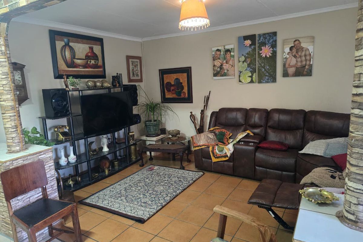 A living room featuring tiled flooring, a stone-clad pillar, and an arched entryway, providing a functional and lived-in space.