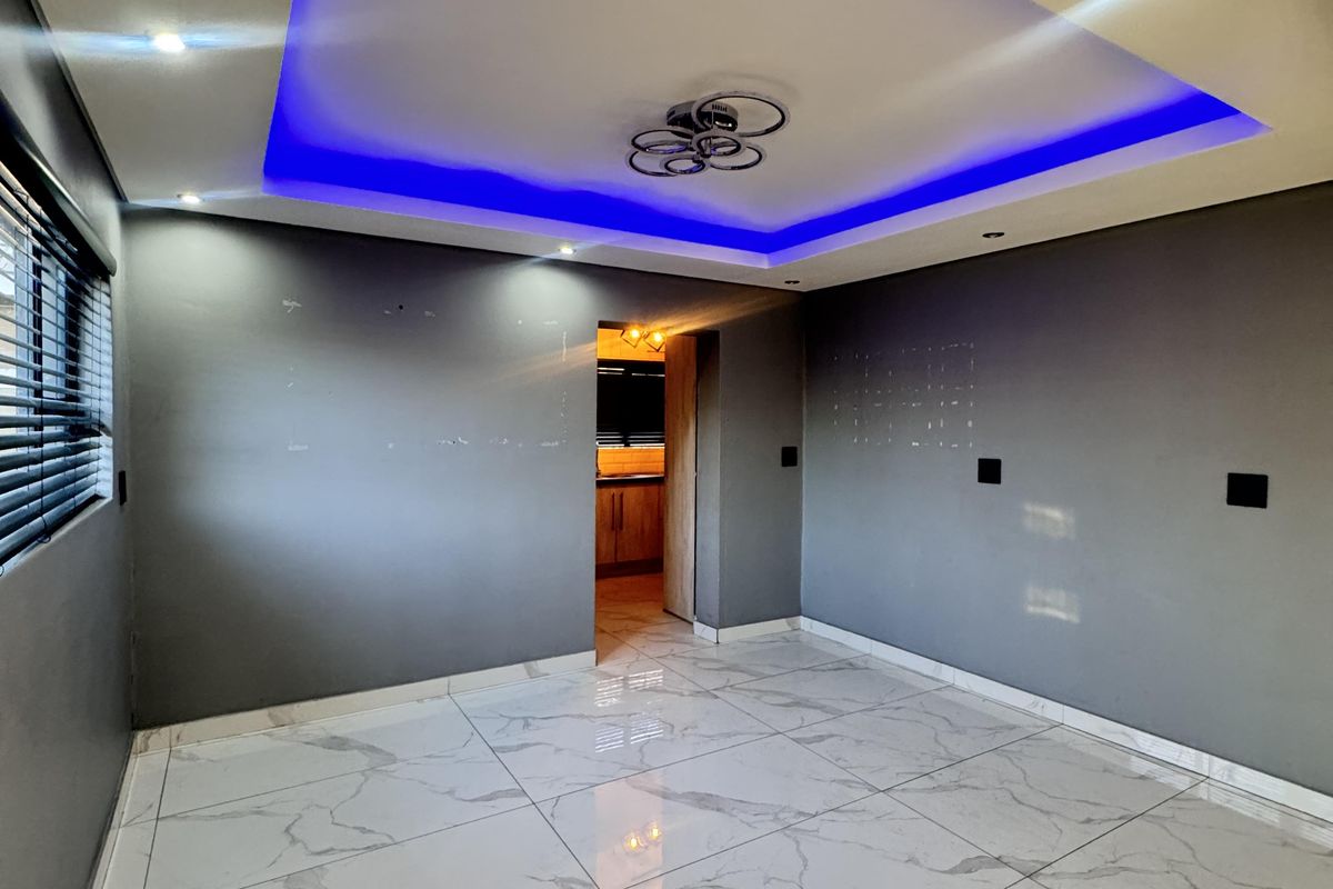 An empty living room featuring large marble-look floor tiles and a modern recessed ceiling with integrated blue LED accent lighting.