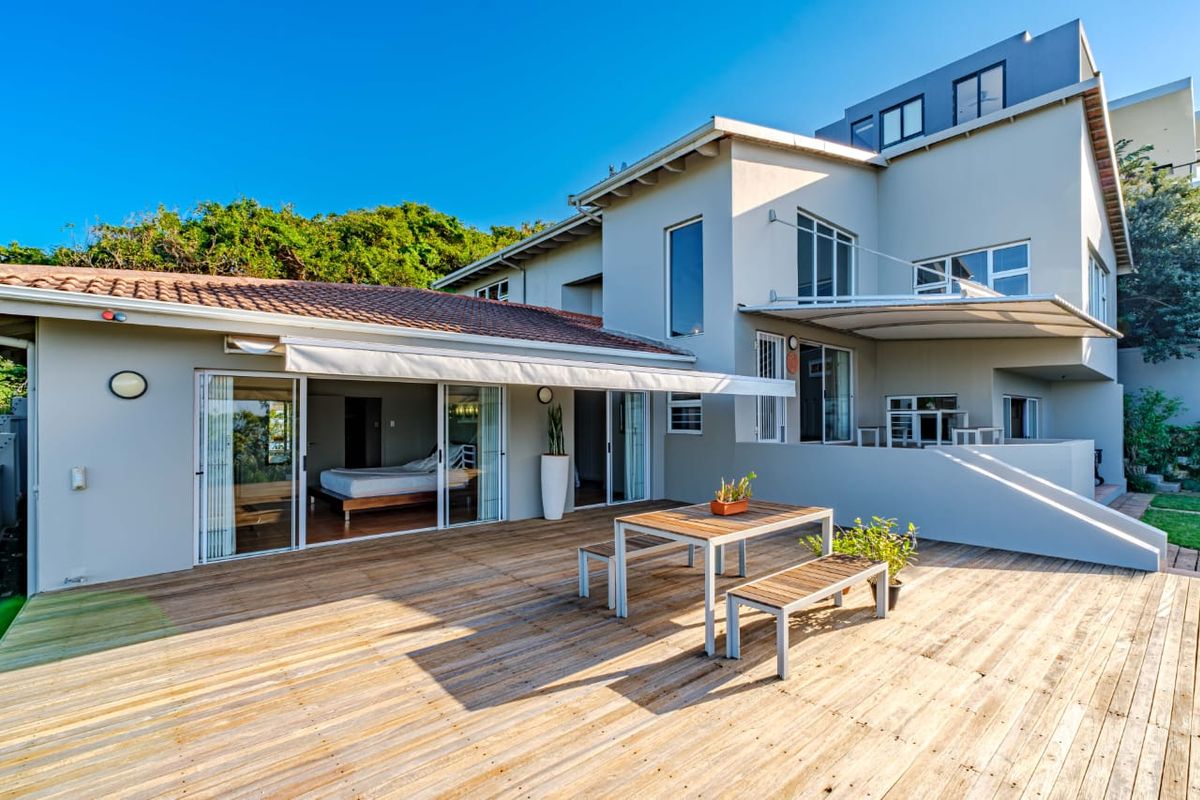 Spacious rear timber deck featuring a retractable awning, providing seamless indoor-outdoor flow through large sliding glass doors to the main residence.