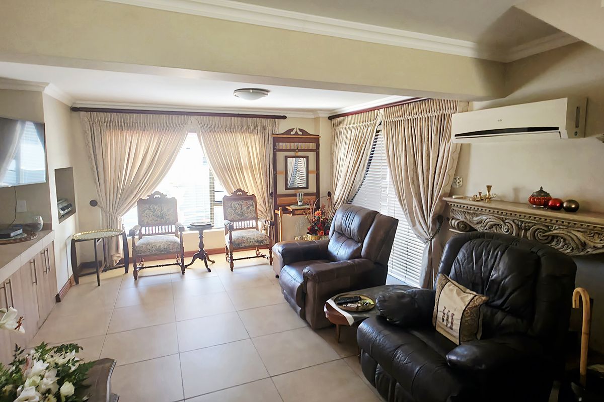 Spacious living room featuring tiled flooring, a decorative fireplace mantel, built-in cabinetry, and a wall-mounted air conditioning unit.