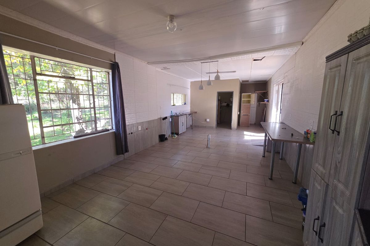 Spacious kitchen area featuring tiled flooring, built-in cabinetry, and large windows, currently in need of finishing touches and ceiling repairs.