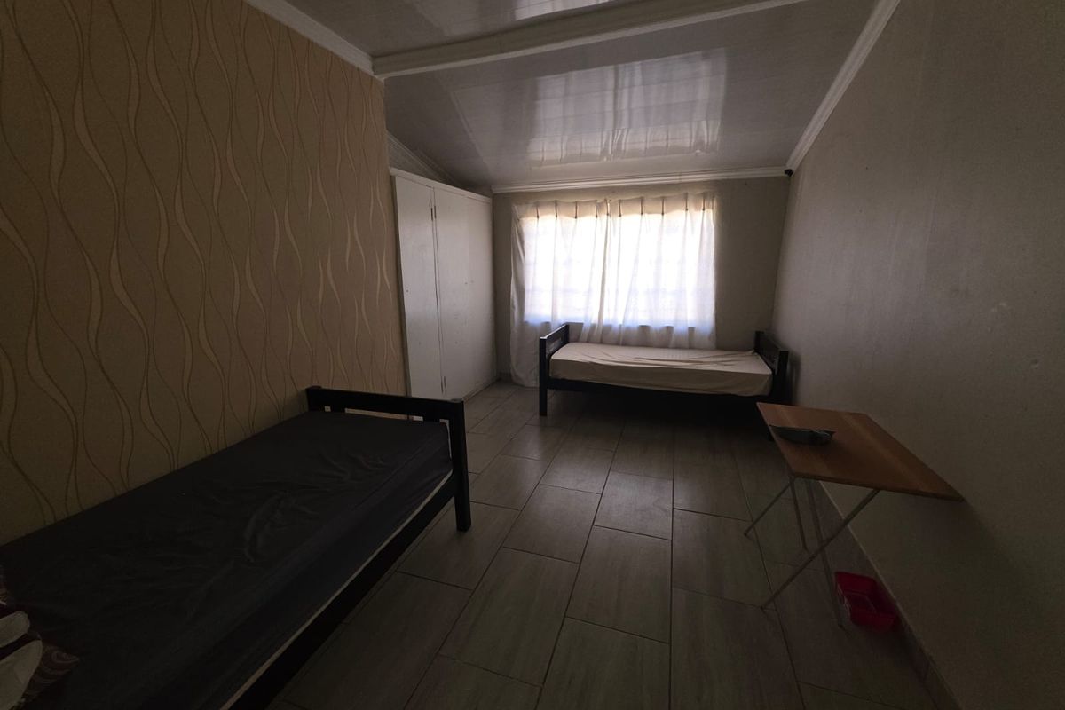 A bedroom featuring tiled flooring, a built-in wardrobe, and a glossy ceiling finish, offering a functional space with potential for cosmetic updates.