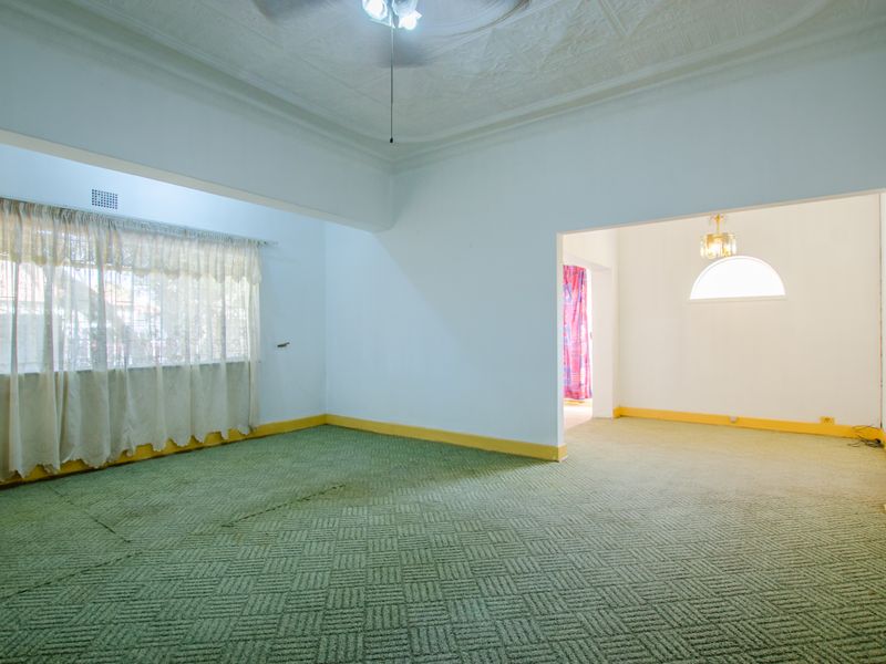Spacious open-plan living area featuring patterned carpeting, decorative ceiling molding, and large windows allowing for natural light.