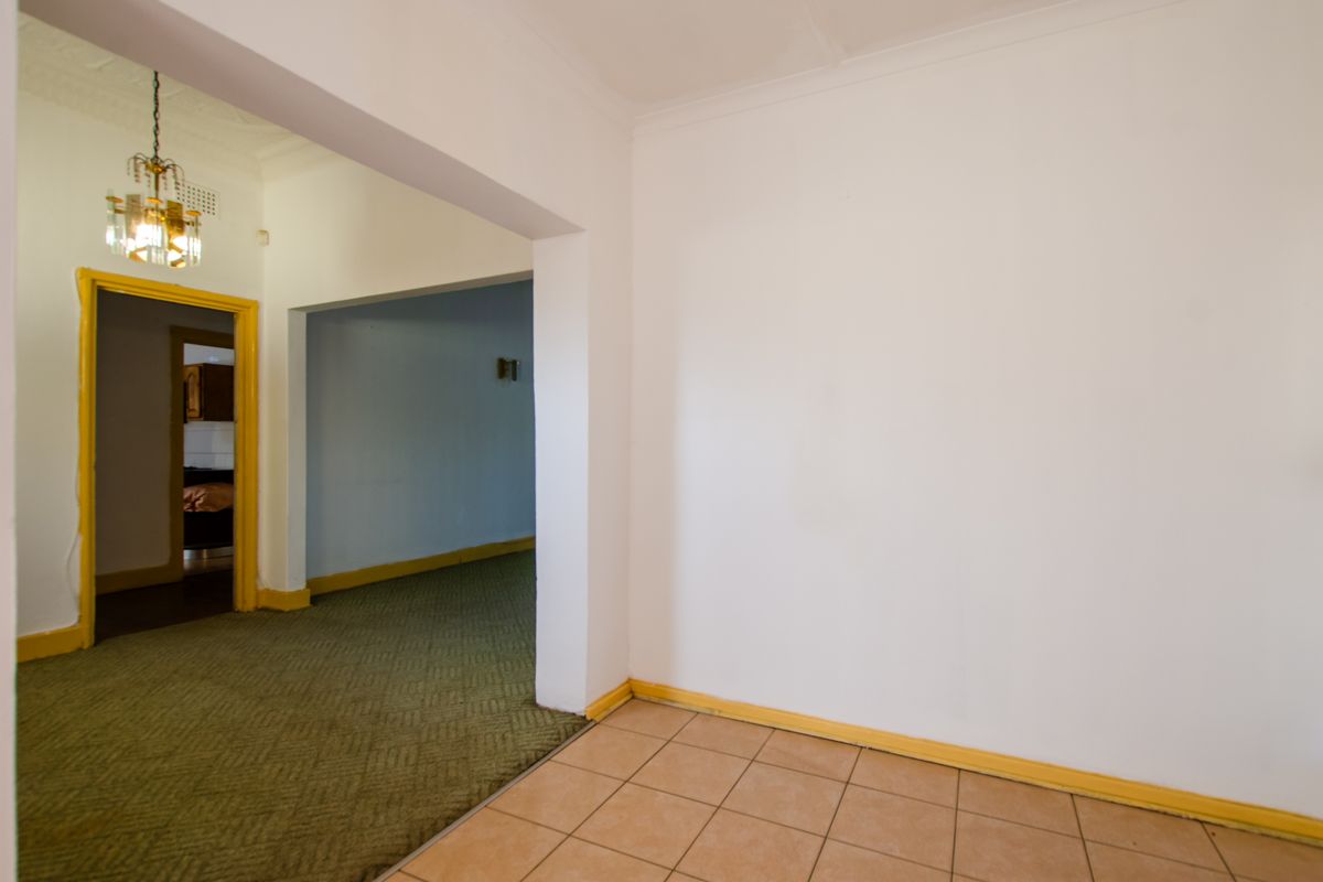 An interior view showing a transition between a tiled area and a carpeted living space with traditional architectural features and dated trim.