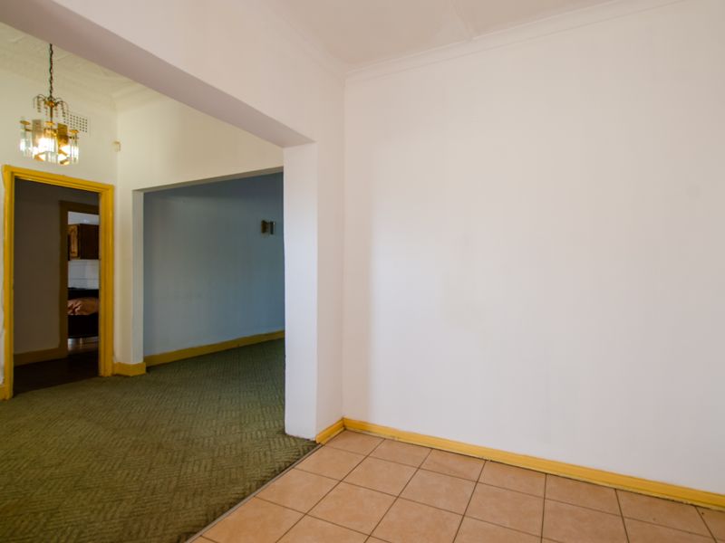 An interior view showing a transition between a tiled area and a carpeted living space with traditional architectural features and dated trim.