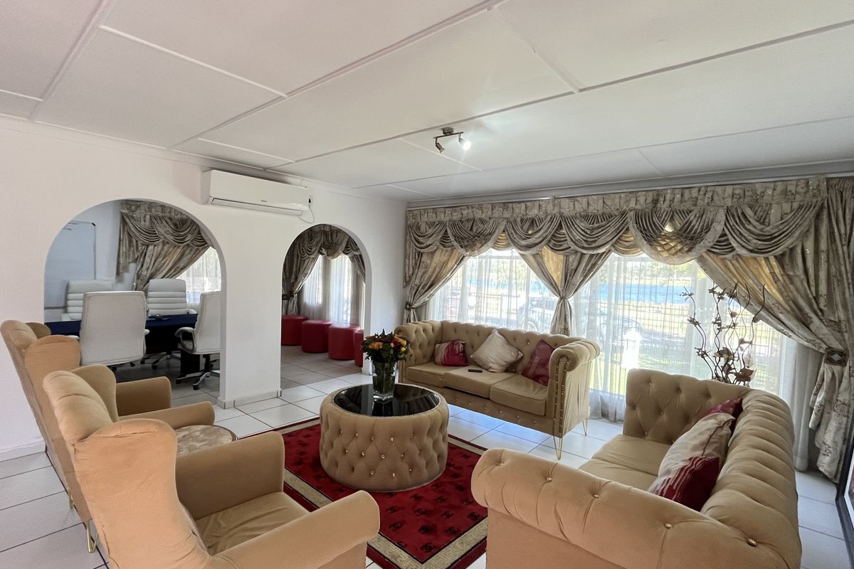 Spacious living area featuring arched room dividers, tiled flooring, and a wall-mounted air conditioning unit.