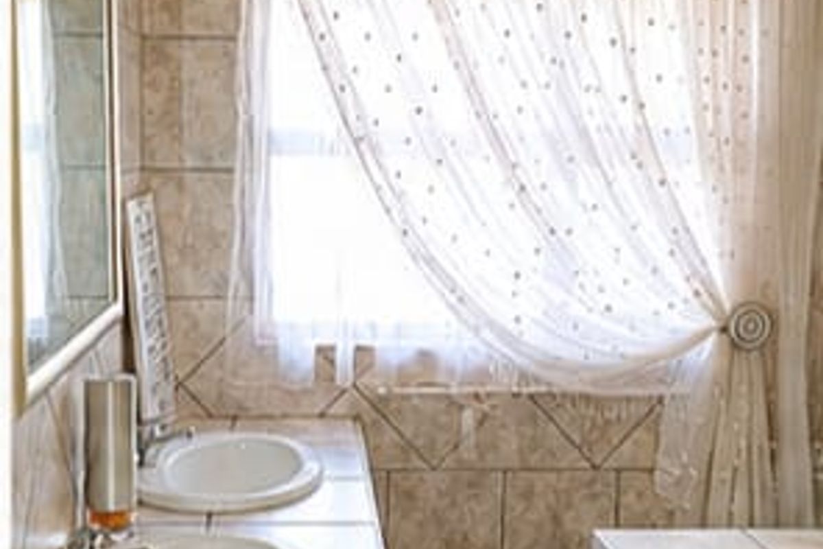 A bathroom featuring a double vanity with tiled countertop, drop-in sinks, and a built-in bathtub with matching wall and floor tiles.
