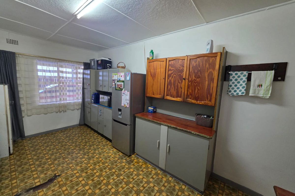 A functional kitchen area featuring built-in cabinetry, laminate countertops, and patterned vinyl flooring, offering potential for modernization and cosmetic updates.