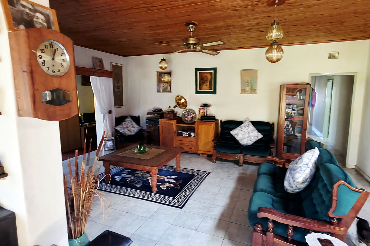 A living room featuring a timber-clad ceiling, ceiling fan, and tiled flooring, with an open-plan layout leading to adjacent areas.