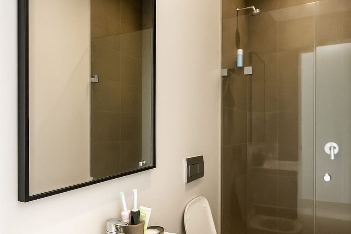 Modern bathroom featuring a sleek vanity with integrated basin, wall-mounted mirror, and a glass-enclosed walk-in shower with contemporary tiling.