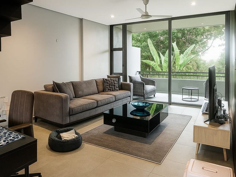 Modern open-plan living area featuring large sliding glass doors leading to a private balcony, recessed lighting, and a sleek staircase.