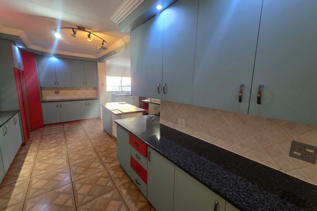 Spacious kitchen featuring extensive cabinetry, dark granite countertops, tiled backsplash, and integrated lighting, offering a functional layout with ample storage space.