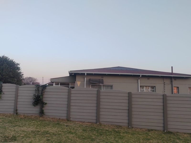 A view of the property's front exterior featuring a secure precast concrete boundary wall with electric fencing and a tiled roof structure.