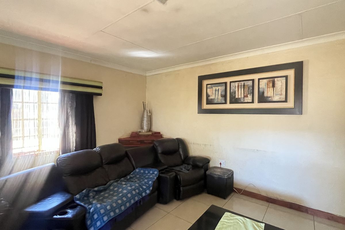 A living room featuring tiled flooring, coved ceilings, and a window with fitted blinds.