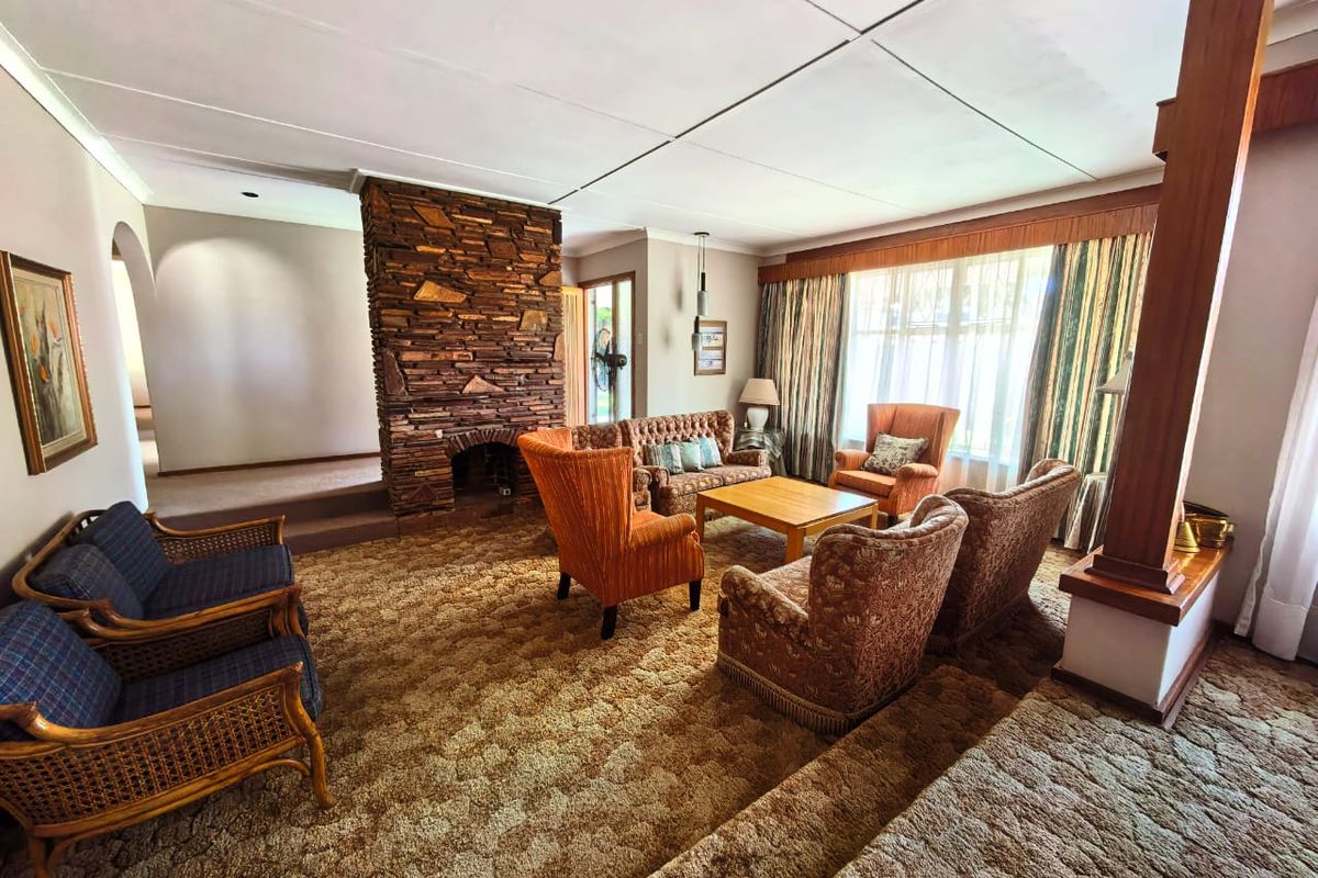 Spacious living room featuring a prominent stone fireplace, split-level flooring, and large windows allowing for natural light.