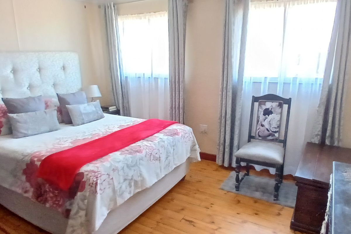 A well-maintained bedroom featuring polished wooden flooring and dual windows with fitted curtain rails.