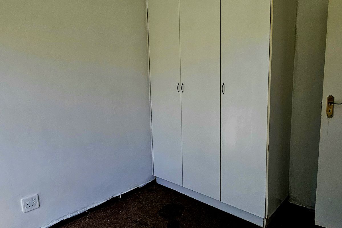 A vacant bedroom featuring a built-in wardrobe, requiring cosmetic updates to the flooring and wall finishes to improve its overall appeal.
