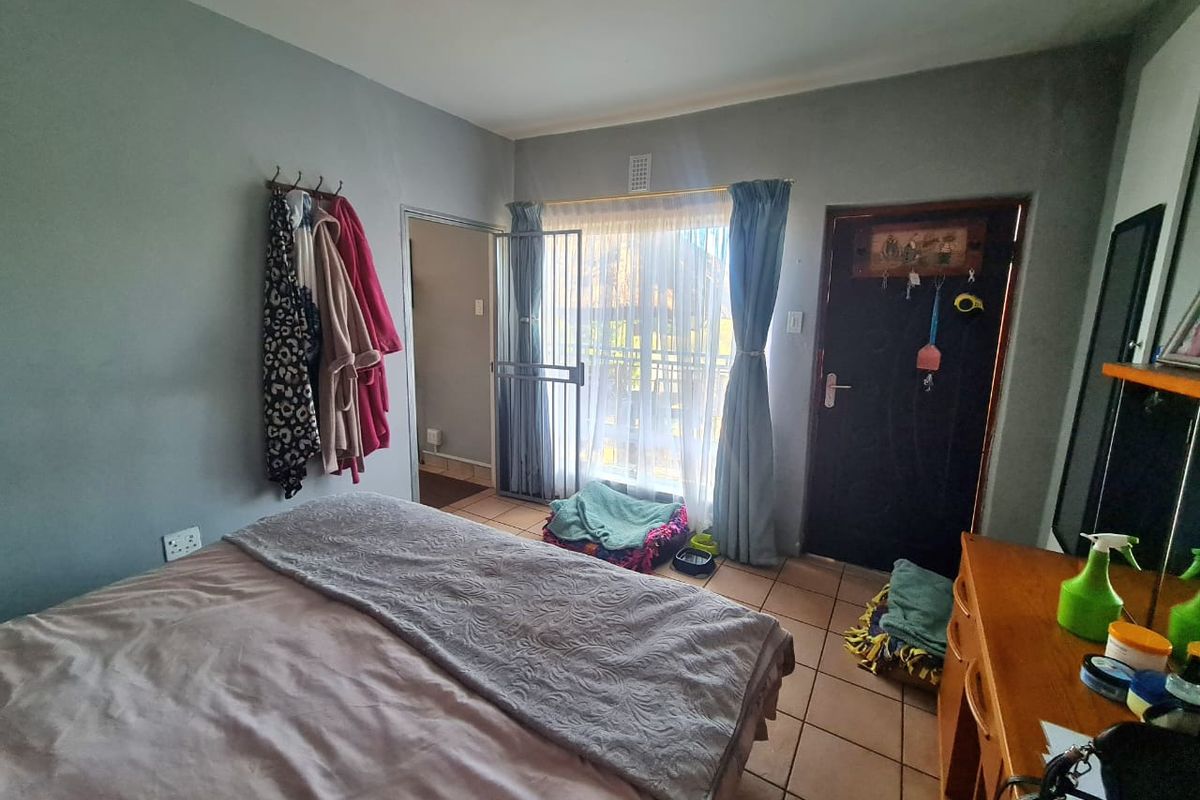 A bedroom featuring tiled flooring, a security gate, and direct access to an outdoor area through a sliding door.