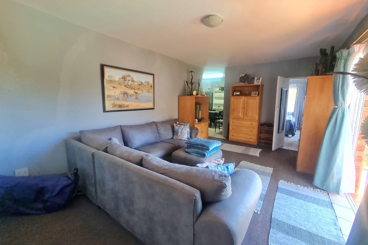 A comfortable living room area featuring neutral wall tones, carpeted flooring, and a sliding glass door providing access to the exterior.
