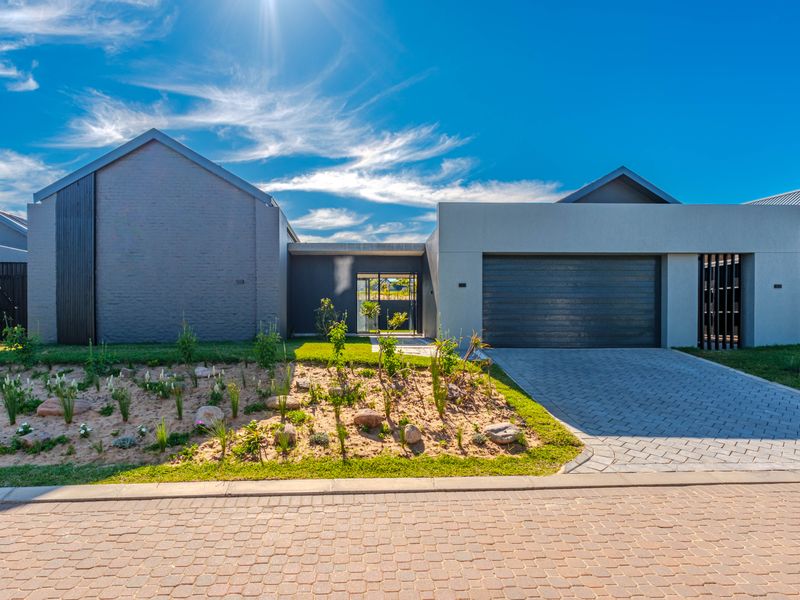 Modern contemporary front elevation featuring a paved driveway, double garage, and neatly landscaped garden with a secure pedestrian entrance.