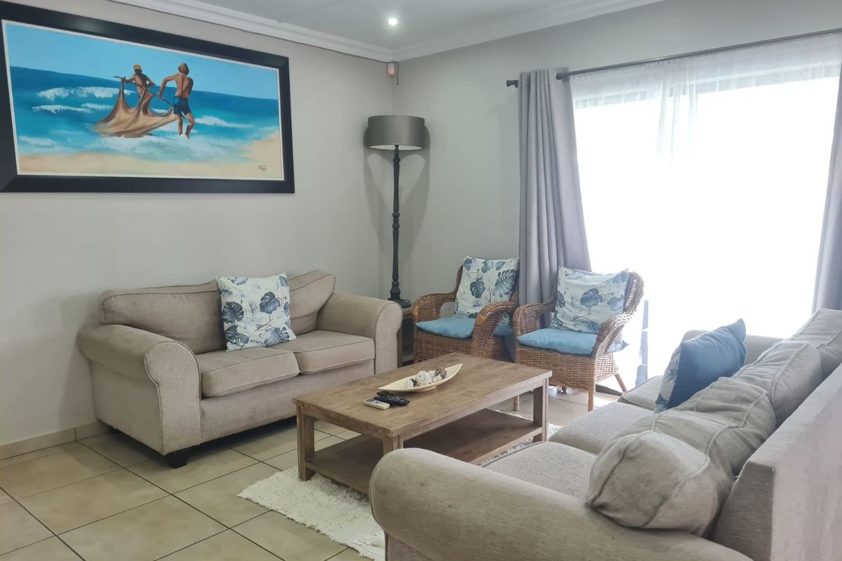 A comfortable living room featuring tiled flooring, recessed downlighting, and a sliding glass door providing natural light.
