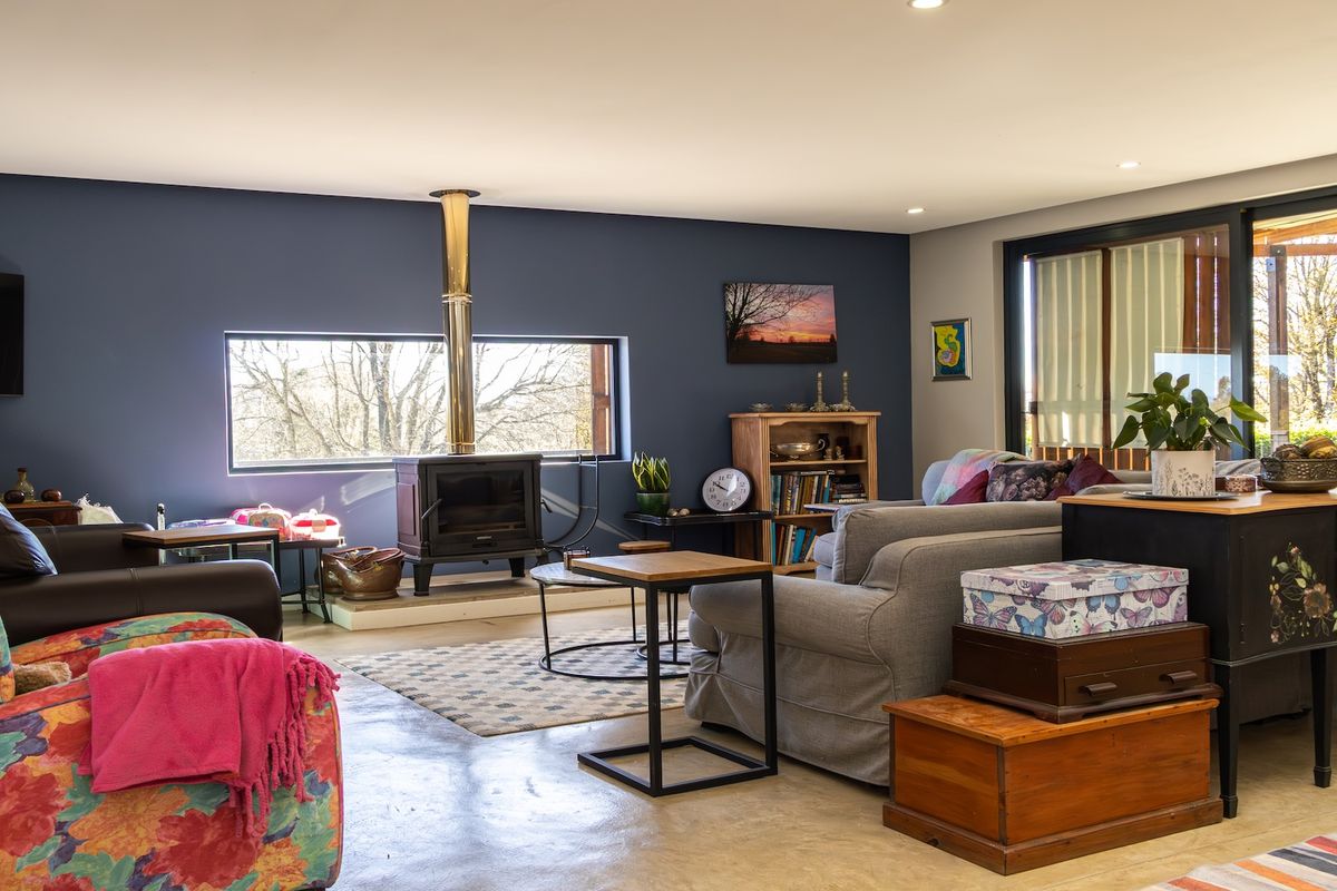 Spacious living room featuring a prominent wood-burning fireplace, polished concrete flooring, and large windows providing natural light and garden views.