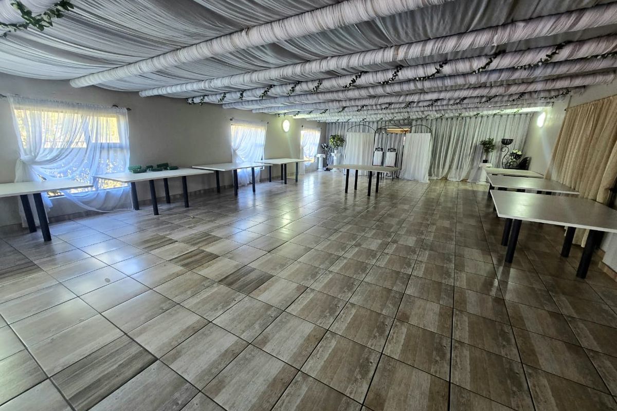 A large, open-plan event or living space featuring wood-look tiled flooring and a decorative draped ceiling treatment.