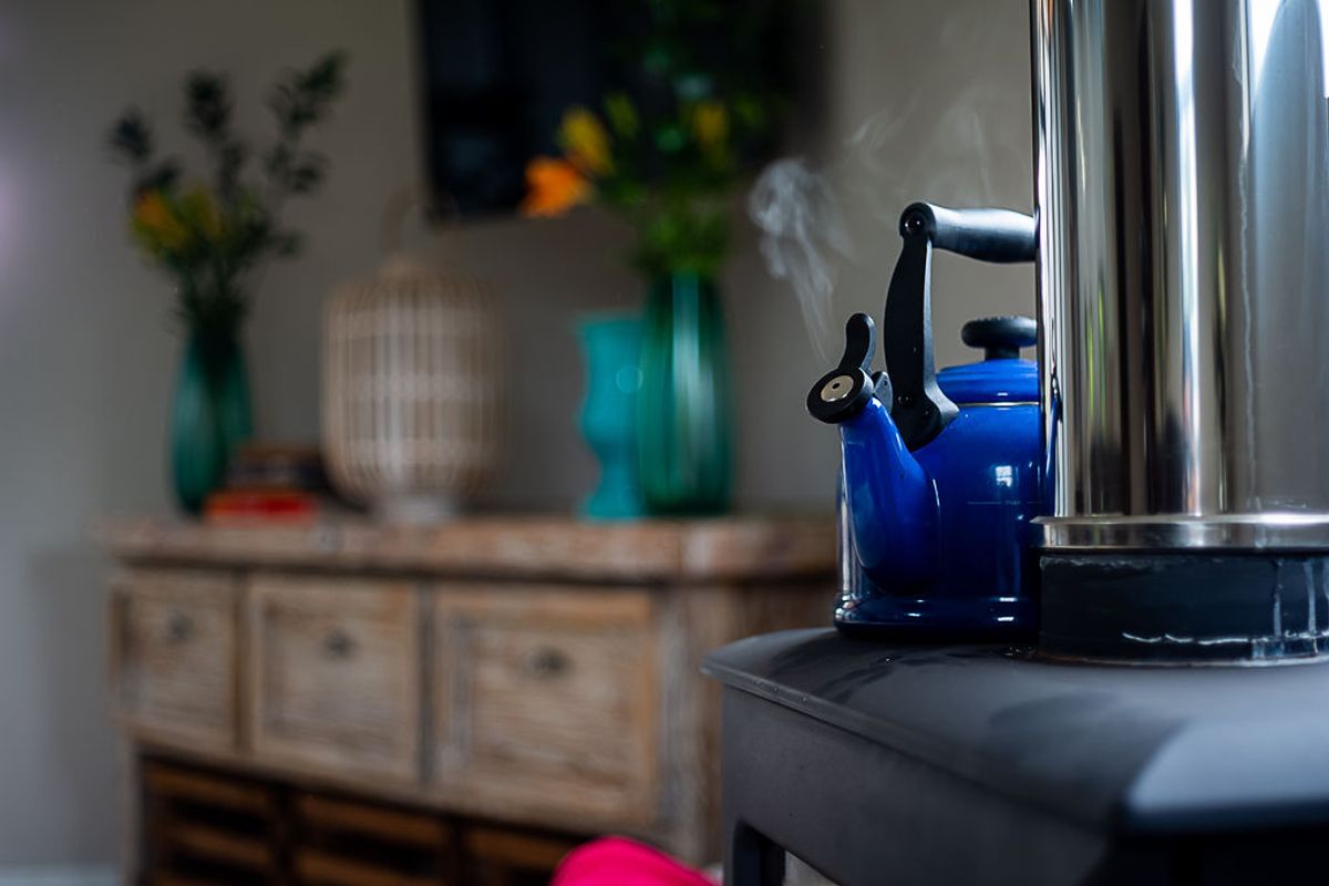 A close-up view of a wood-burning stove with a kettle, highlighting the cozy atmosphere of the living space.